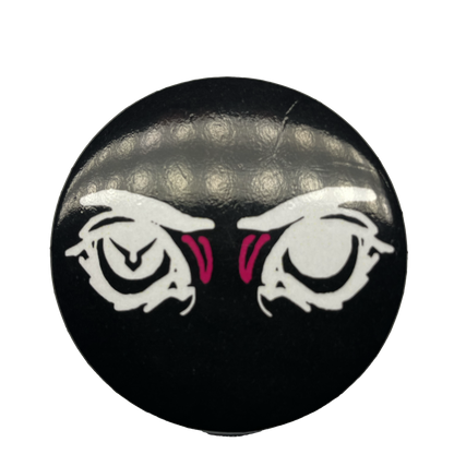 A round pin with a black background featuring an eye design with pink irises and a logo resembling a stylized face in the center.